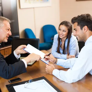 A man handing over papers to two people.