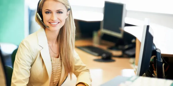 A woman sitting at her desk with a headset on.