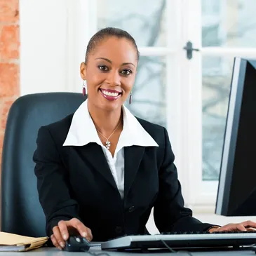 A woman sitting at her desk in front of two computers.