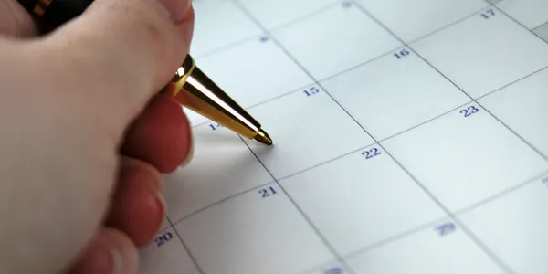 A person writing on the calendar of an event.