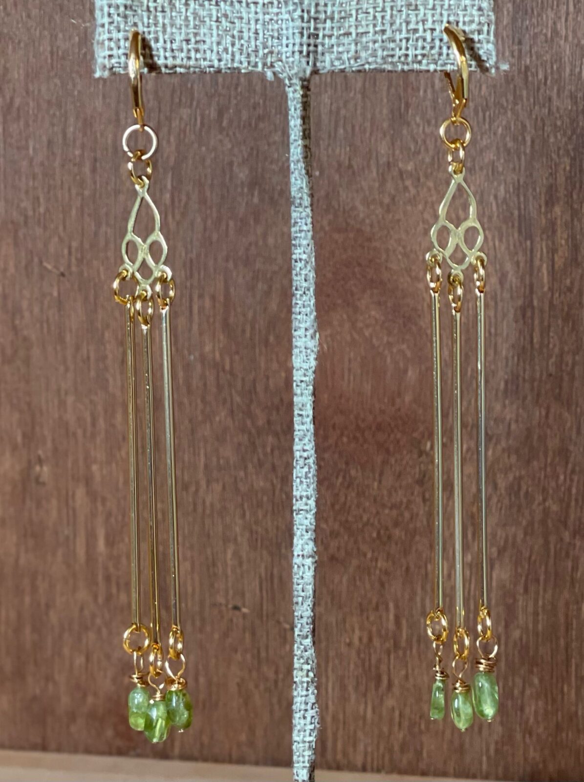 A pair of gold earrings hanging on a stand.
