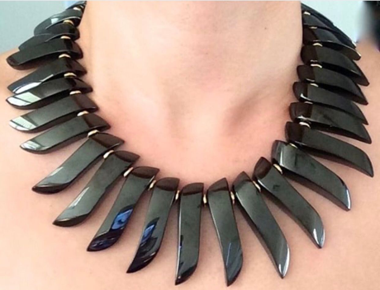 A woman wearing a necklace with black and gold accents.